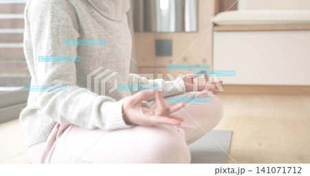 Meditating woman in light-gray turtleneck and pink sweats on yoga mat at home, with blue overlays Meditating woman in light-gray turtleneck and pink sweats on yoga mat at home, with blue overlays 141071712