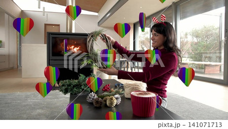 Smiling woman arranging twig wreath at home wearing burgundy sweater, festive headband, copy space Smiling woman arranging twig wreath at home wearing burgundy sweater, festive headband, copy space 141071713