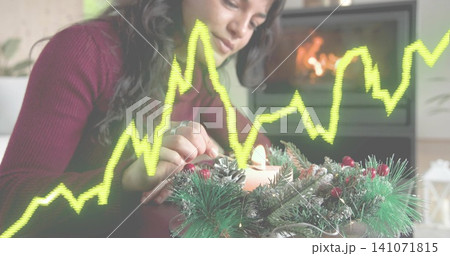 Leaning woman in burgundy knit lighting candle in table wreath at home, with yellow-green overlay Leaning woman in burgundy knit lighting candle in table wreath at home, with yellow-green overlay 141071815