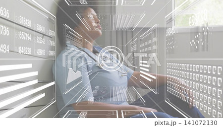 Monitoring female nurse studying holographic panels in clinic, in blue scrubs with stethoscope 141072130