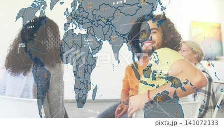 Smiling curly-haired man in yellow tee joining discussion in meeting room with map overlay 141072133