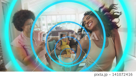 Dancing right-side woman in light tank top smiling in living room with smartphone blue-ring overlay Dancing right-side woman in light tank top smiling in living room with smartphone blue-ring overlay 141072416