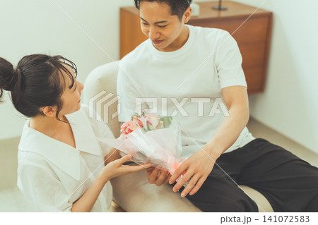 花束を手渡す男性を見上げる女性 花束を手渡す男性を見上げる女性 141072583