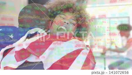 Laughing woman wrapped in American flag being lifted by friends in classroom, with market overlay 141072656