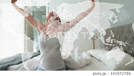 Stretching woman wearing white sleepwear raising arms in bedroom, with bed, headboard, map overlay Stretching woman wearing white sleepwear raising arms in bedroom, with bed, headboard, map overlay 141072788
