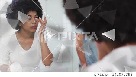 Applying woman in white top placing contact at vanity with white case, mirror triangles, copy space Applying woman in white top placing contact at vanity with white case, mirror triangles, copy space 141072792