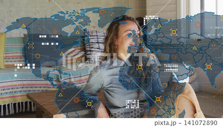 Leaning back adult woman wearing light-gray top and tan shorts at home, viewing AR map overlay 141072890
