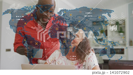 Pointing man redshirt guiding woman floral-top using laptop in kitchen, with digital map and mug Pointing man redshirt guiding woman floral-top using laptop in kitchen, with digital map and mug 141072902