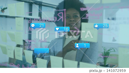 Pointing woman in gray blazer touching glass wall at office, yellow sticky notes and social icons Pointing woman in gray blazer touching glass wall at office, yellow sticky notes and social icons 141072959