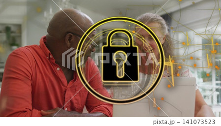 Leaning red-shirted man and patterned-blouse woman using laptop at home, with gold padlock overlay 141073523