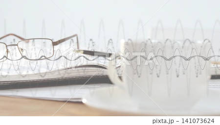 Featuring notebook with rectangular glasses and pen lying on pages on wooden desk, waveform overlay 141073624