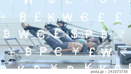Doing Pilates, three women lying on reformers in Pilates studio wearing leggings currency overlay Doing Pilates, three women lying on reformers in Pilates studio wearing leggings currency overlay 141073730