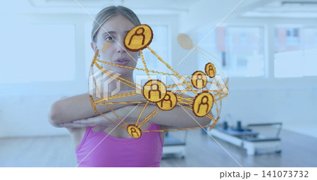Standing woman crossing arms in pink tank top in fitness studio, digital overlay, Pilates reformers Standing woman crossing arms in pink tank top in fitness studio, digital overlay, Pilates reformers 141073732
