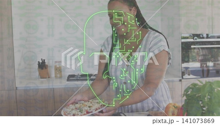 Smiling woman holding salad plate at kitchen island wearing striped dress, green circuit overlay Smiling woman holding salad plate at kitchen island wearing striped dress, green circuit overlay 141073869