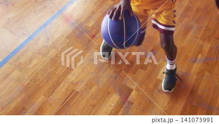 Dribbling Chinese teen holding blue-purple basketball on gym court, in yellow jersey maroon shorts 141073991