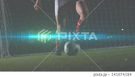 Standing soccer player on stadium turf, wearing red socks and black cleats with ball by goal Standing soccer player on stadium turf, wearing red socks and black cleats with ball by goal 141074184