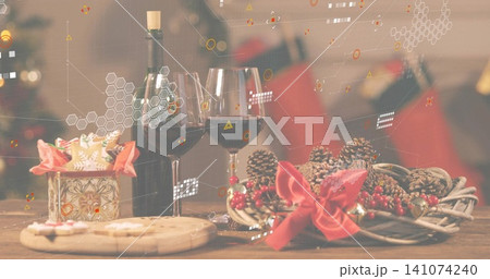Showing holiday scene on wooden table at home, with two wine glasses, green bottle, wreath, cookies Showing holiday scene on wooden table at home, with two wine glasses, green bottle, wreath, cookies 141074240