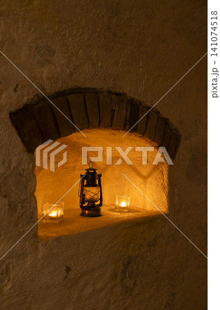 Oil lamp and candles illuminating old stone niche 141074518