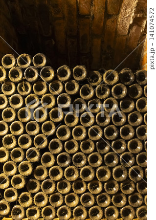 Stacking wine bottles in old dusty cellar for aging Stacking wine bottles in old dusty cellar for aging 141074572