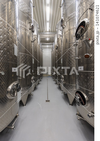 Row of large industrial tanks inside a modern winemaking facility Row of large industrial tanks inside a modern winemaking facility 141074621