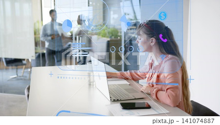 Working woman in salmon blouse typing on laptop at meeting table, with AR overlays, smartphone 141074887