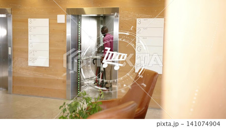 Guiding man in magenta top, khakis pushing red bicycle into lobby elevator, with shopping cart HUD 141074904