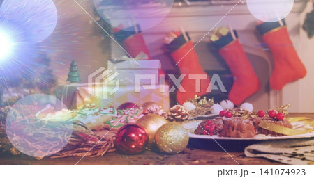 Displaying festive table scene glowing on wood surface in living room with desserts and red baubles Displaying festive table scene glowing on wood surface in living room with desserts and red baubles 141074923
