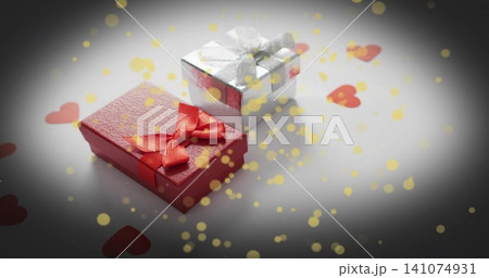 Showing two wrapped gifts on white table, red textured box, silver box, heart confetti, gold bokeh Showing two wrapped gifts on white table, red textured box, silver box, heart confetti, gold bokeh 141074931