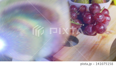 Showing red grape cluster on cutting board at kitchen table, lens flare and bowl, copy space 141075158