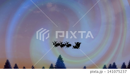 Gliding silhouetted sleigh Santa in coat, hat holding reins past four reindeer beneath aurora swirl 141075237