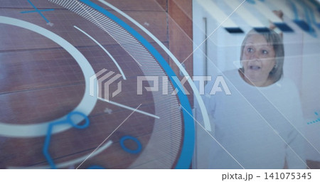 Looking startled senior woman in white top behind glass in hallway, HUD rings overlay, copy space 141075345