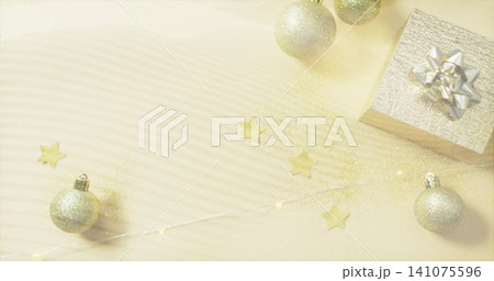 Displaying silver-wrapped gift box with metal bow, gold baubles on ribbed cream surface, copy space Displaying silver-wrapped gift box with metal bow, gold baubles on ribbed cream surface, copy space 141075596