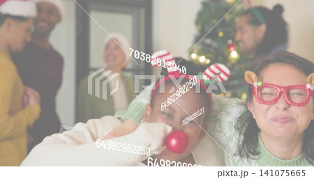 Holding red bauble, two women wearing green knit top and reindeer glasses at home, numeric overlay Holding red bauble, two women wearing green knit top and reindeer glasses at home, numeric overlay 141075665