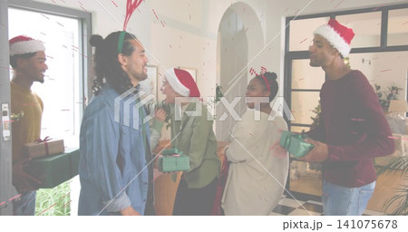 Gathering group of six adults exchanging green gifts and greeting in entryway, with Santa hats Gathering group of six adults exchanging green gifts and greeting in entryway, with Santa hats 141075678