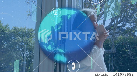 Hugging senior woman holding ceramic mug at sliding door with holographic globe icons, copy space Hugging senior woman holding ceramic mug at sliding door with holographic globe icons, copy space 141075988