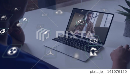 Watching participant in blue top tapping pad at home office with laptop, eco icons, potted plant 141076130