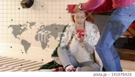 Cradling woman wrapped in blanket holding red mug near low hearth, red-sweatered man offering mug Cradling woman wrapped in blanket holding red mug near low hearth, red-sweatered man offering mug 141076428