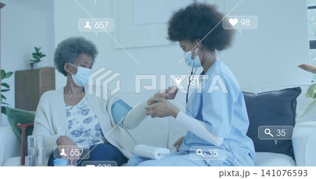 Measuring nurse in blue scrubs fitting BP cuff on senior patient on sofa, showing monitor overlays Measuring nurse in blue scrubs fitting BP cuff on senior patient on sofa, showing monitor overlays 141076593