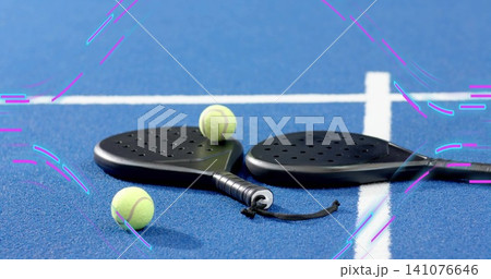 Showing black padel paddles resting on blue court near white lines with three balls and strap Showing black padel paddles resting on blue court near white lines with three balls and strap 141076646
