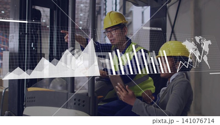 Pointing pair wearing yellow hard hats, vest, checking AR charts on tablet by forklift in warehouse 141076714