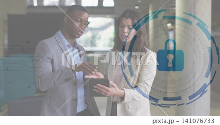 Pointing man and woman wearing suits reviewing tablet in office lobby, showing padlock overlay Pointing man and woman wearing suits reviewing tablet in office lobby, showing padlock overlay 141076733