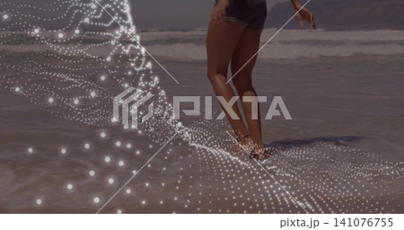 Walking lower body in denim shorts along sandy shoreline, dotted overlay, holding shell, copy space Walking lower body in denim shorts along sandy shoreline, dotted overlay, holding shell, copy space 141076755