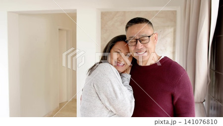Leaning couple embracing at home, wearing burgundy sweater and grey sweatshirt with eyeglasses Leaning couple embracing at home, wearing burgundy sweater and grey sweatshirt with eyeglasses 141076810