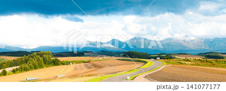 夏の終わりの北海道美瑛町の丘の上から見た十勝岳連峰と先に続く道 141077177