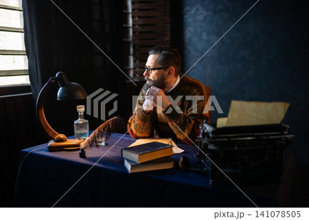Thoughtful man writer sitting at a vintage writing desk Thoughtful man writer sitting at a vintage writing desk 141078505
