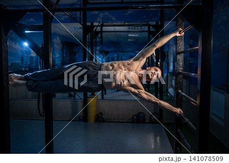 Strong athlete performing a human flag exercise on metal wall rungs Strong athlete performing a human flag exercise on metal wall rungs 141078509