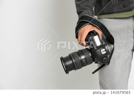 Professional photographer with modern camera on light background in studio, closeup Professional photographer with modern camera on light background in studio, closeup 141079565