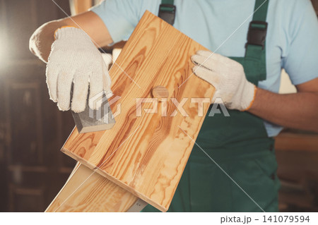 Professional carpenter polishing wooden drawer in workshop, closeup Professional carpenter polishing wooden drawer in workshop, closeup 141079594