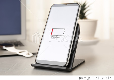 Mobile phone charging with wireless device on light grey stone table Mobile phone charging with wireless device on light grey stone table 141079717