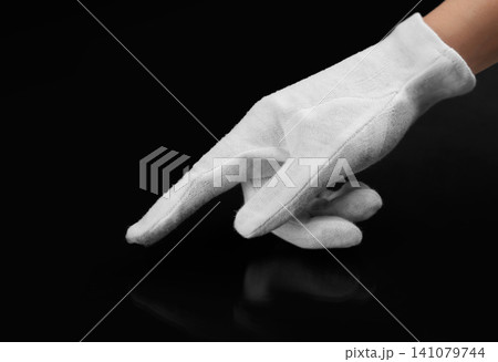 Person in white glove checking cleanliness of black background, closeup Person in white glove checking cleanliness of black background, closeup 141079744